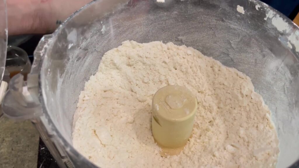 Flour, sugar, and butter for the strawberry hand pie dough in a food processor.